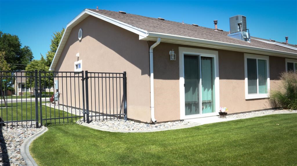 a brown house with a yard and a black fence