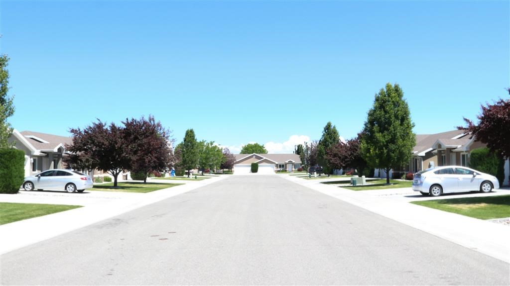 a suburban street with cars parked on the side of the road