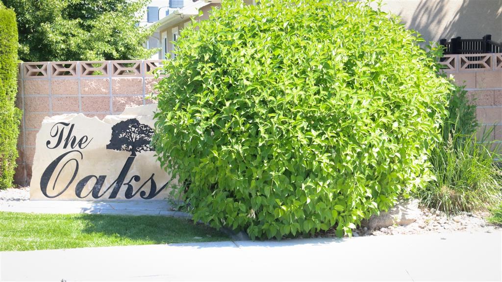 a sign for the oaks in front of a bush