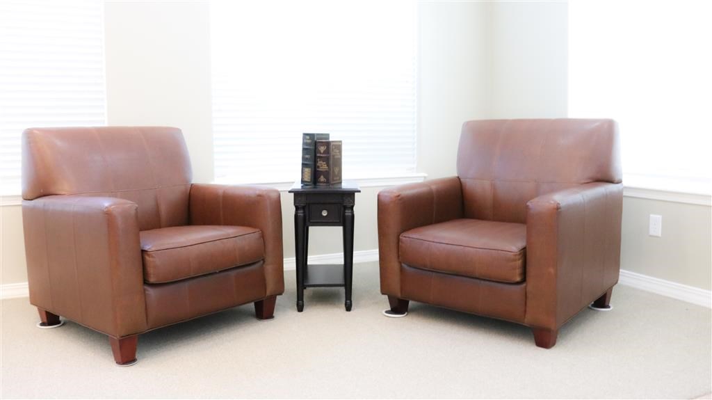 two leather chairs in a room next to a window