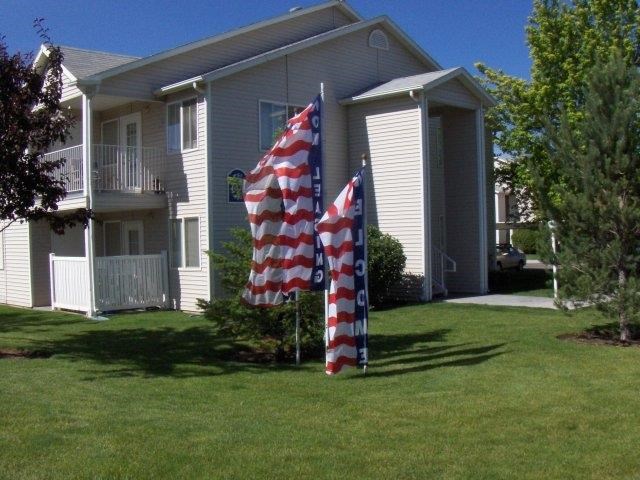 two flags in the grass in front of a house