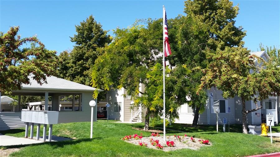 a white house with a flag and a yard with flowers