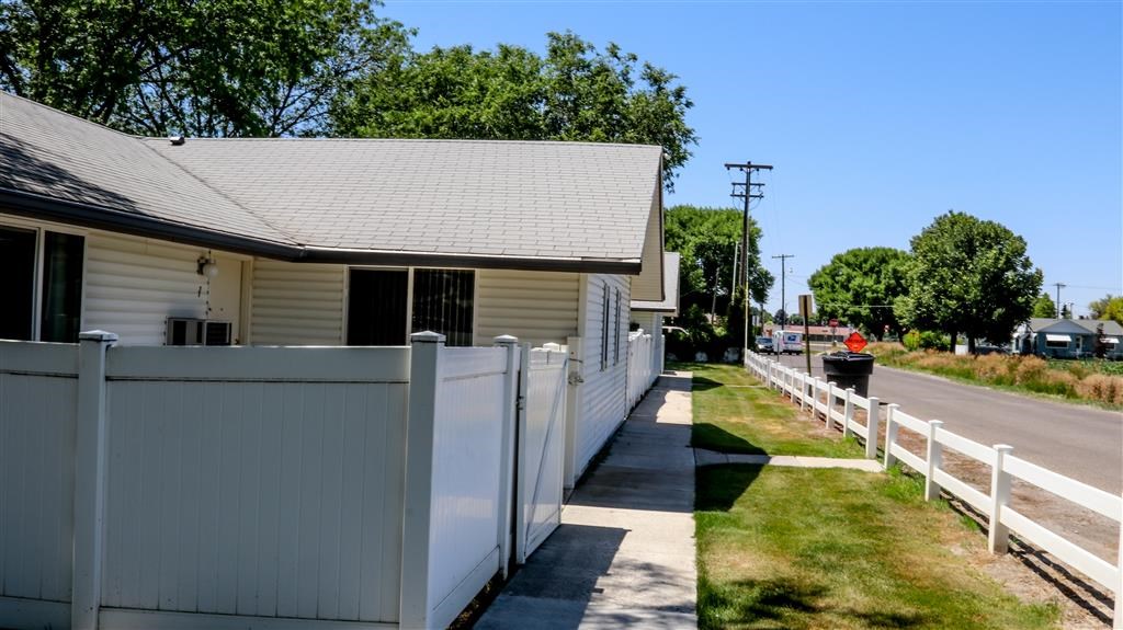 a white building with a white fence next to a street