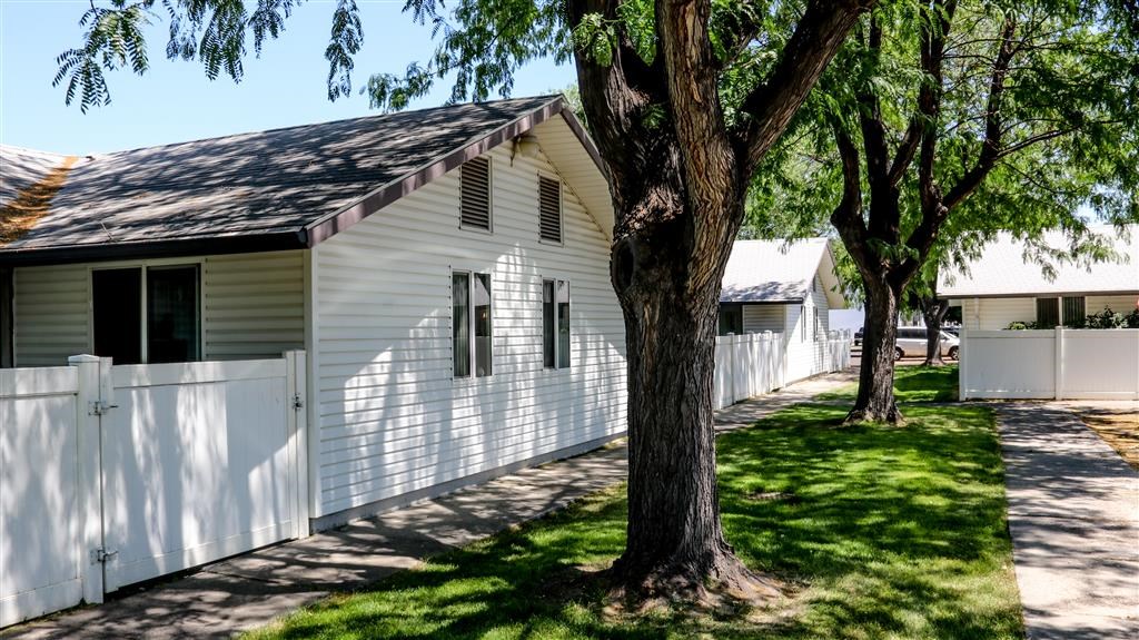 a white house with a white fence and trees