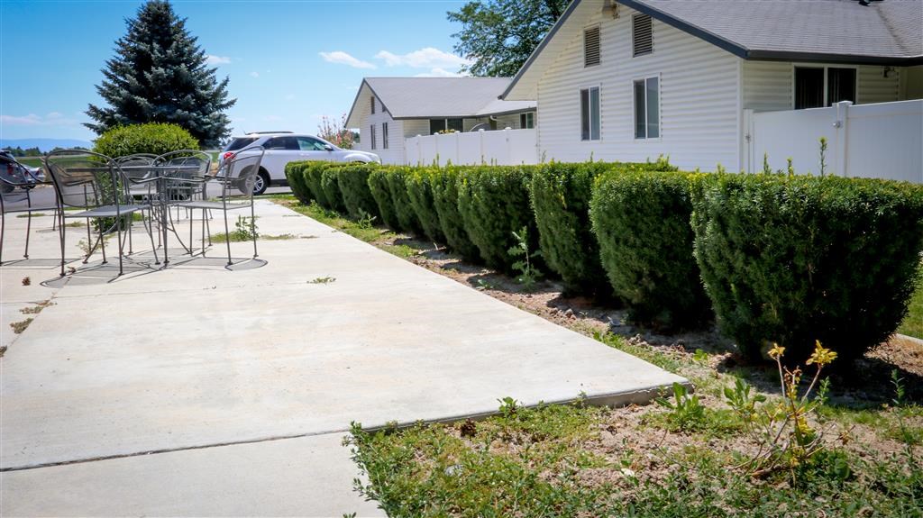 a sidewalk in front of a house with a table and chairs