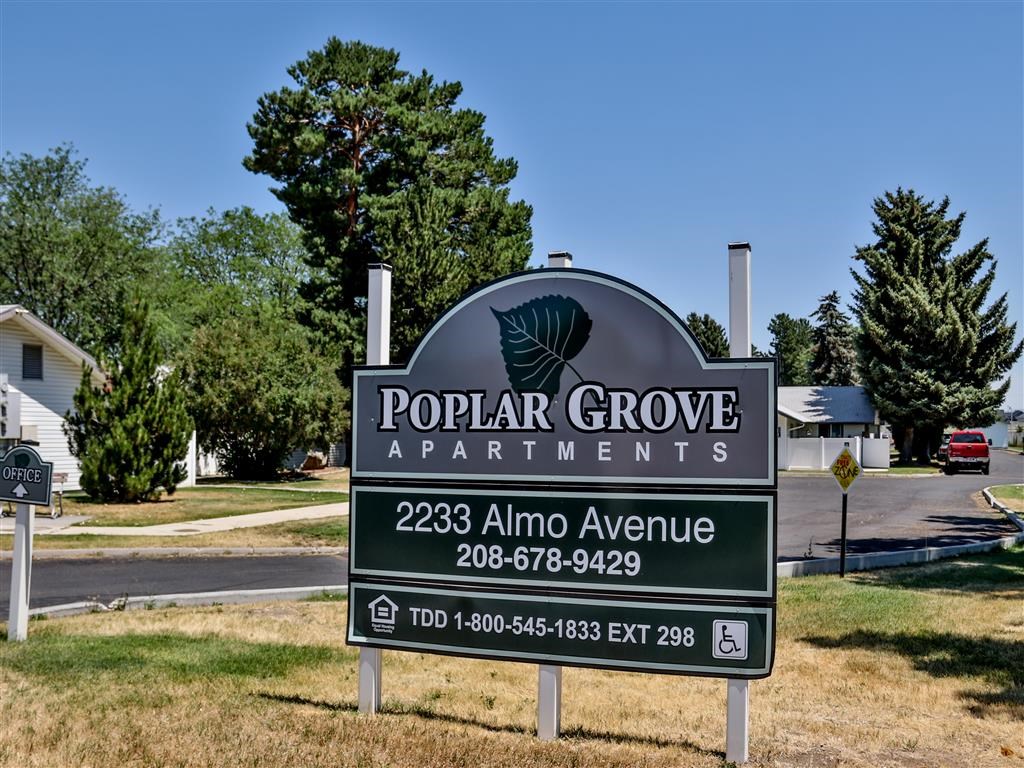 a sign for popular grove apartments on the side of a road