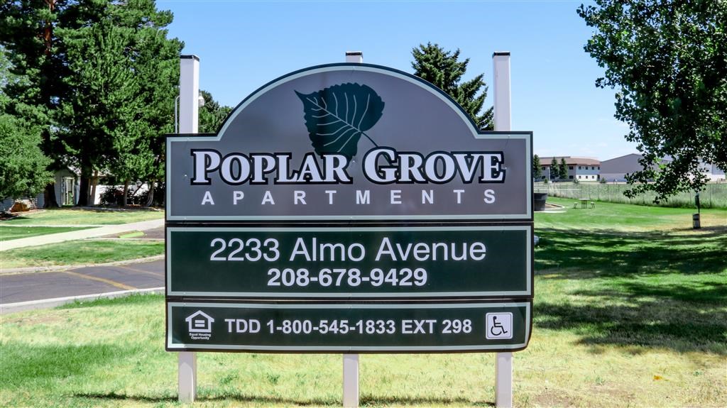 a sign for popular grove apartments in a park