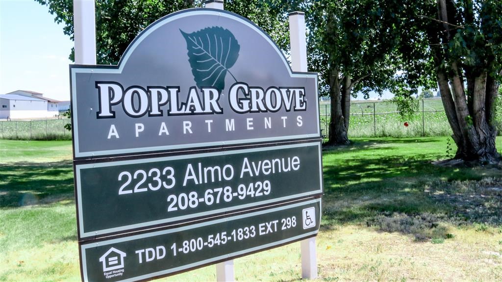 a sign for popular grove apartments on the side of a field