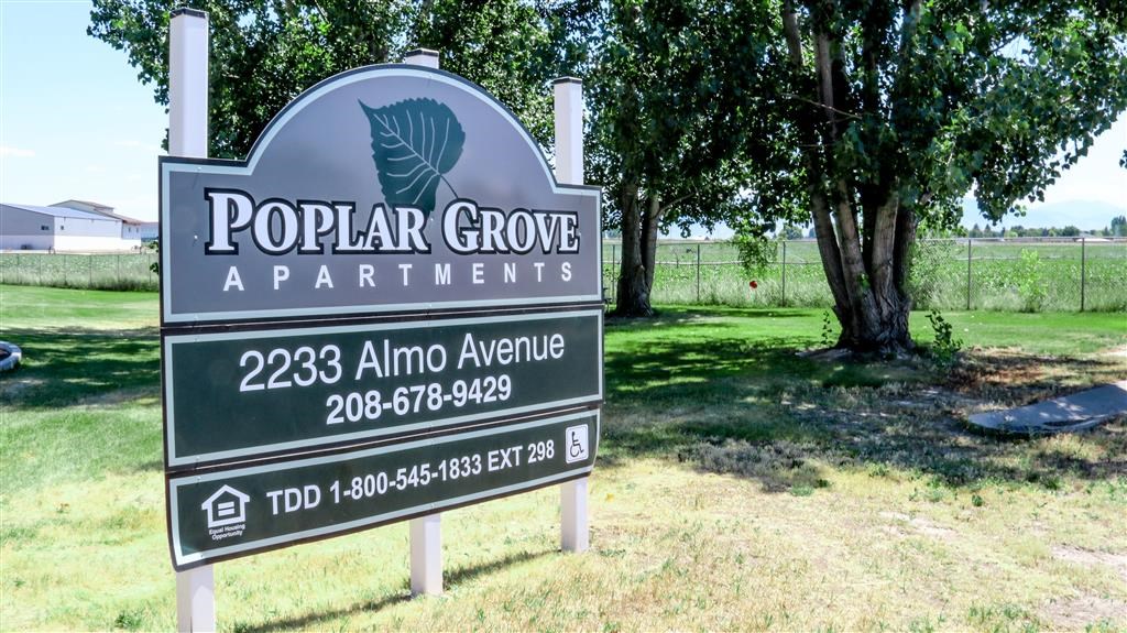 a sign for popular grove apartments on the side of a field