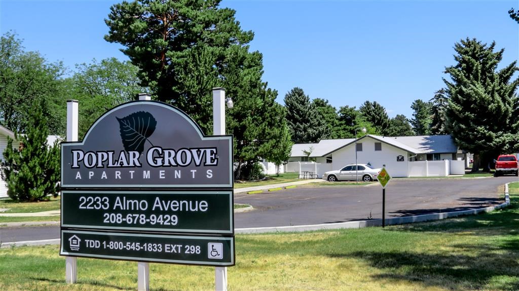 a sign for the popular grove apartments on the side of a road
