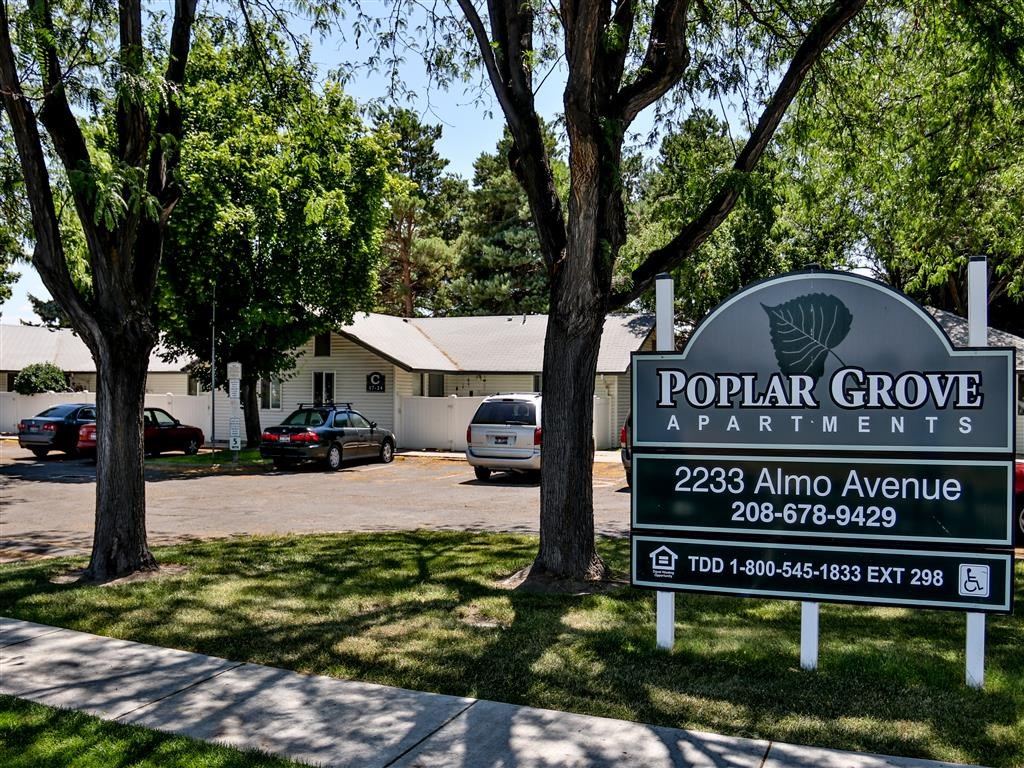 a sign for popular grove apartments in front of a parking lot