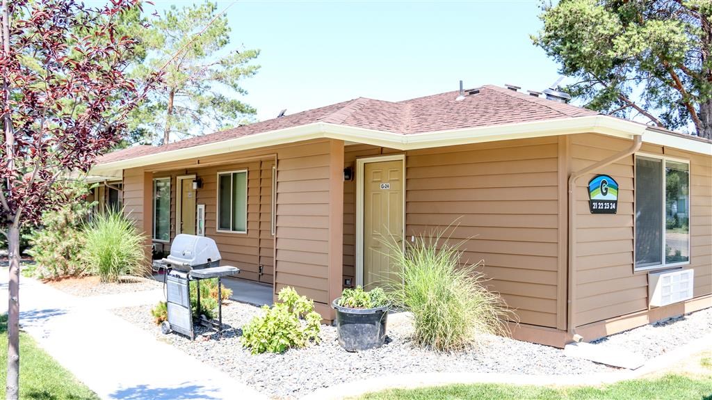 a small brown house with a porch and a grill