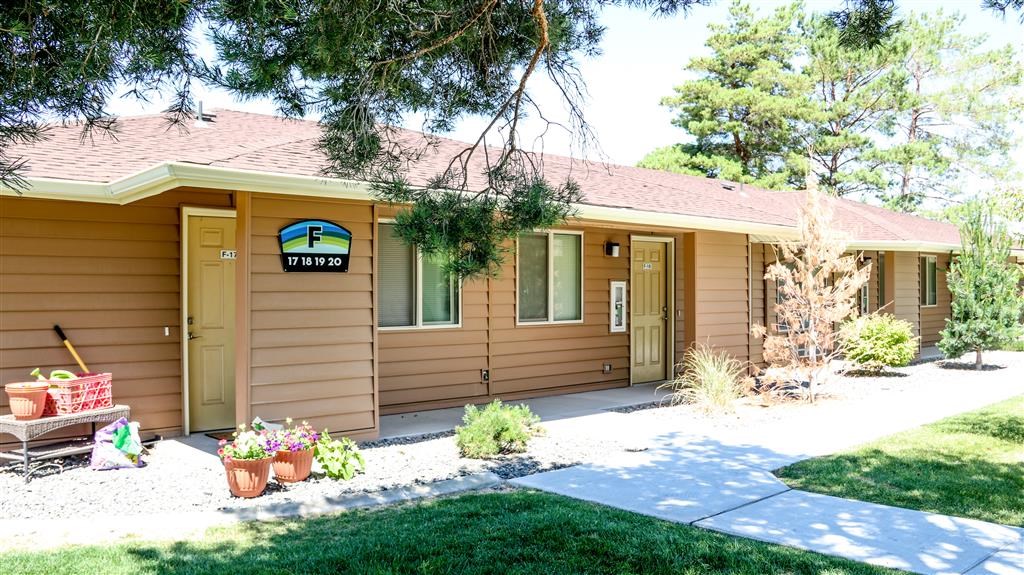 a small brown house with a porch and a driveway