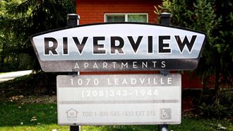 a sign for riverview apartments in front of a house