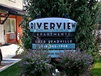 a sign for riverview apartments in front of trees
