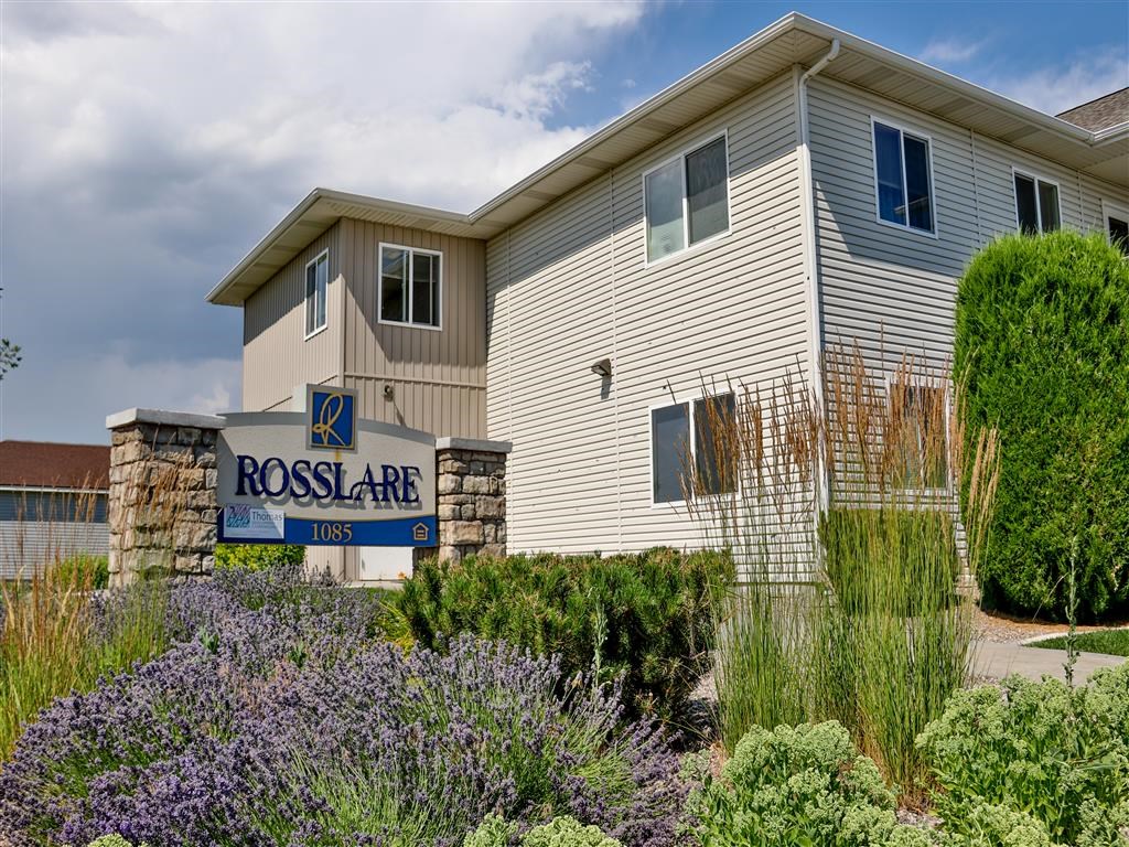 a building with a rose arc nursing home sign in front of flowers