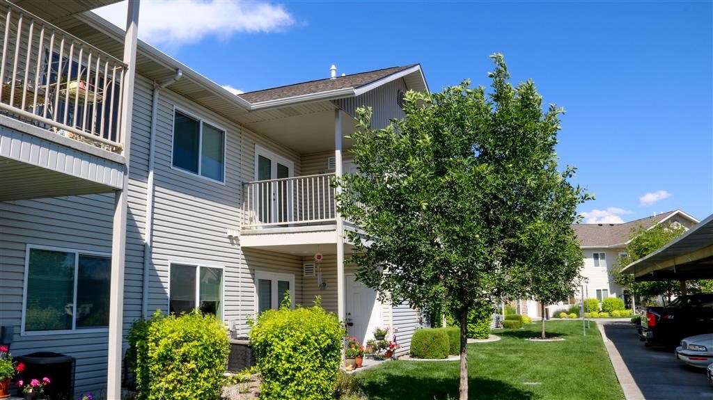 the exterior of an apartment building with a yard and trees