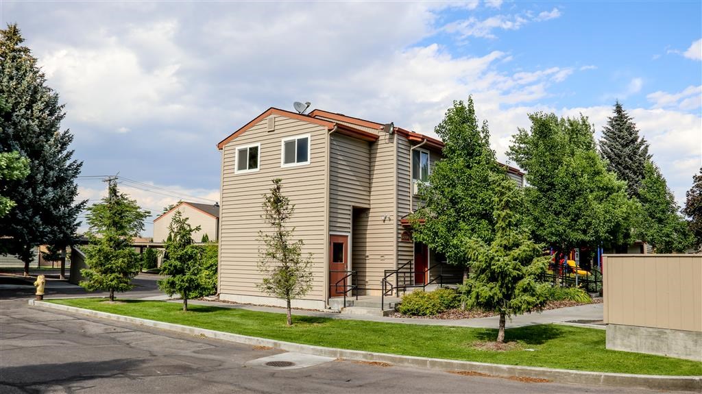 a house on the corner of a street with trees