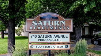 a sign for saturn apartments in front of some trees