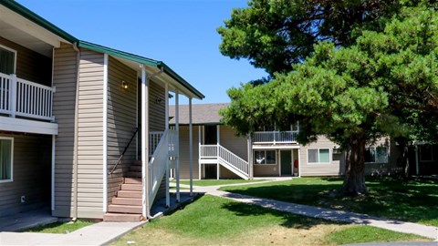 an apartment building with stairs and a tree in front of it