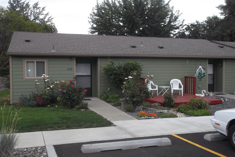 a green house with a sidewalk in front of it