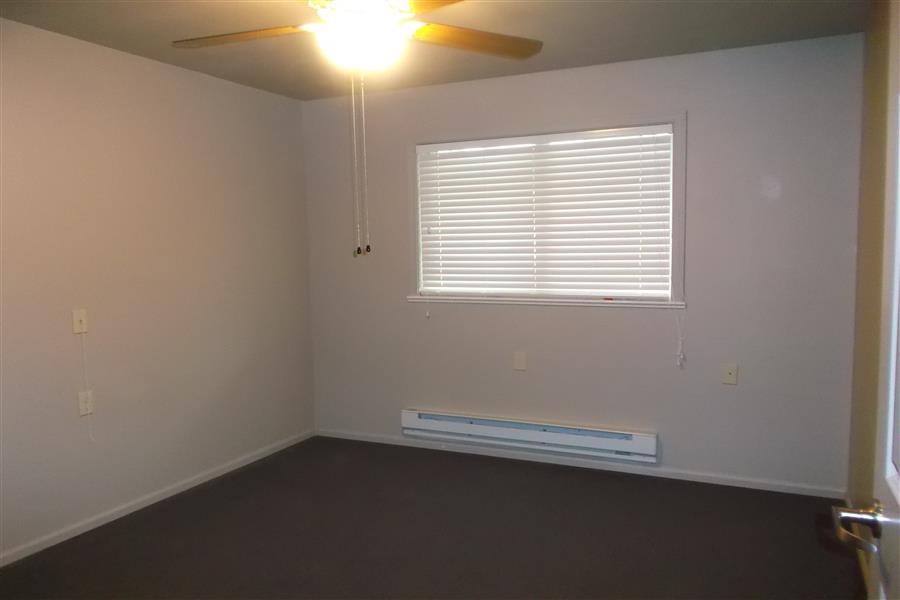 an empty room with a ceiling fan and a window