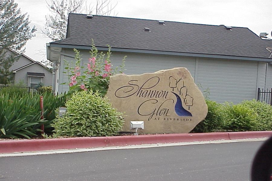 a sign on the side of a street in front of a house