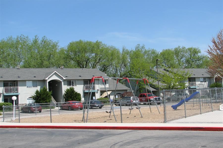 a playground with a swing set in front of a house