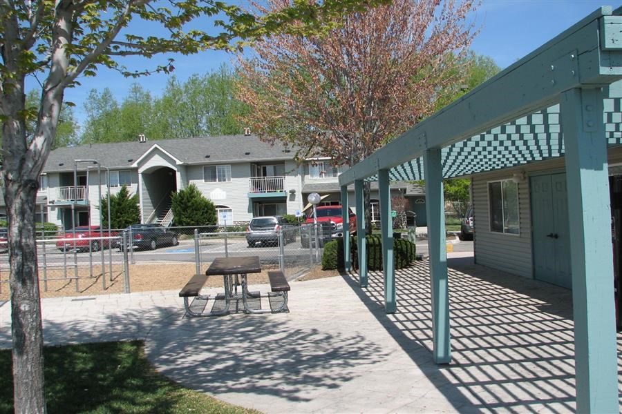 a patio with a picnic table in front of an apartment building