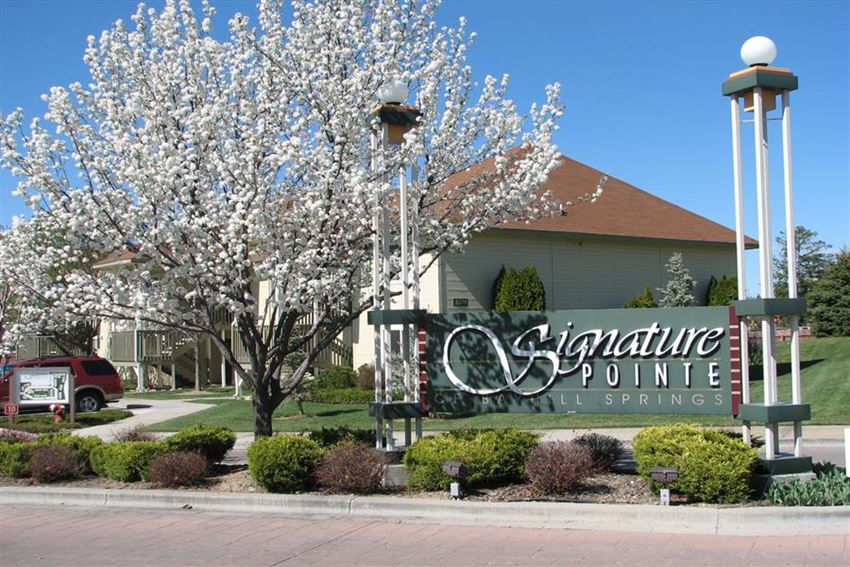 a sign in front of a building with a flowering tree