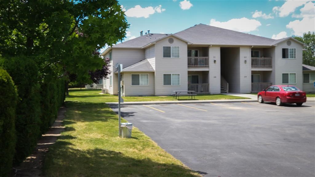 a white apartment building with a red car parked in a parking lot