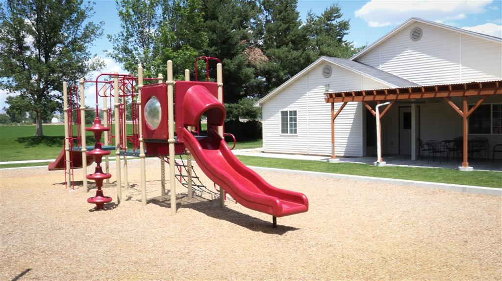 a playground with a swing set and slides in front of a house
