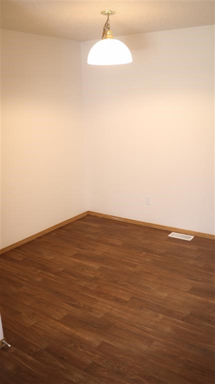 an empty room with wood floors and a lamp