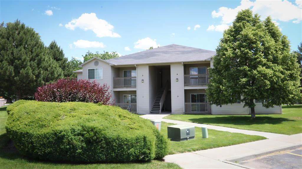 an apartment building with a lawn and trees