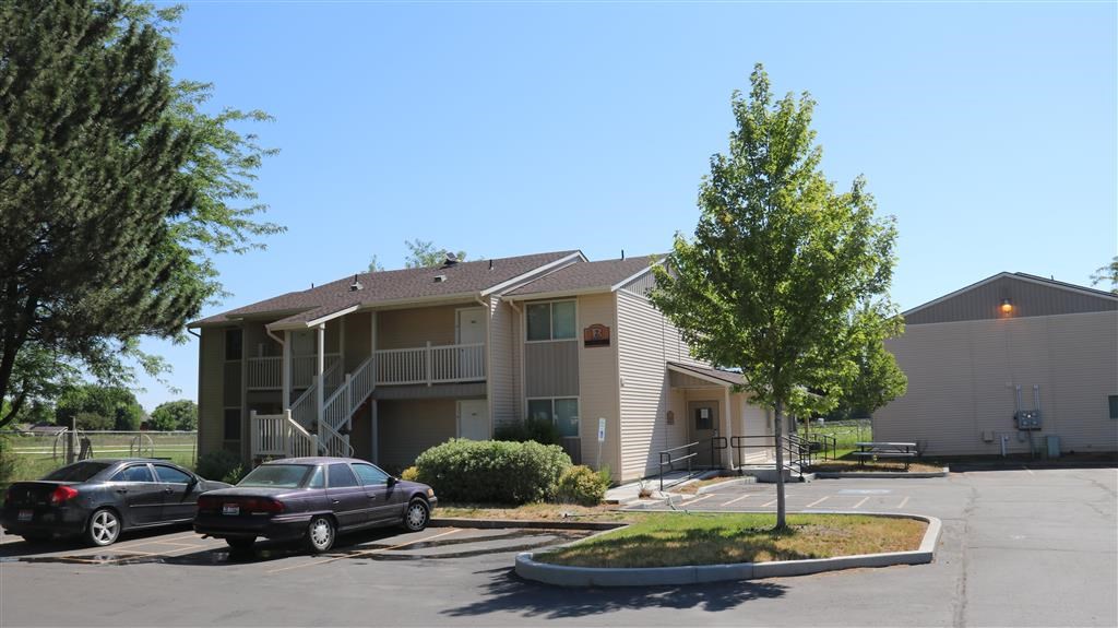 an apartment building with cars parked in a parking lot