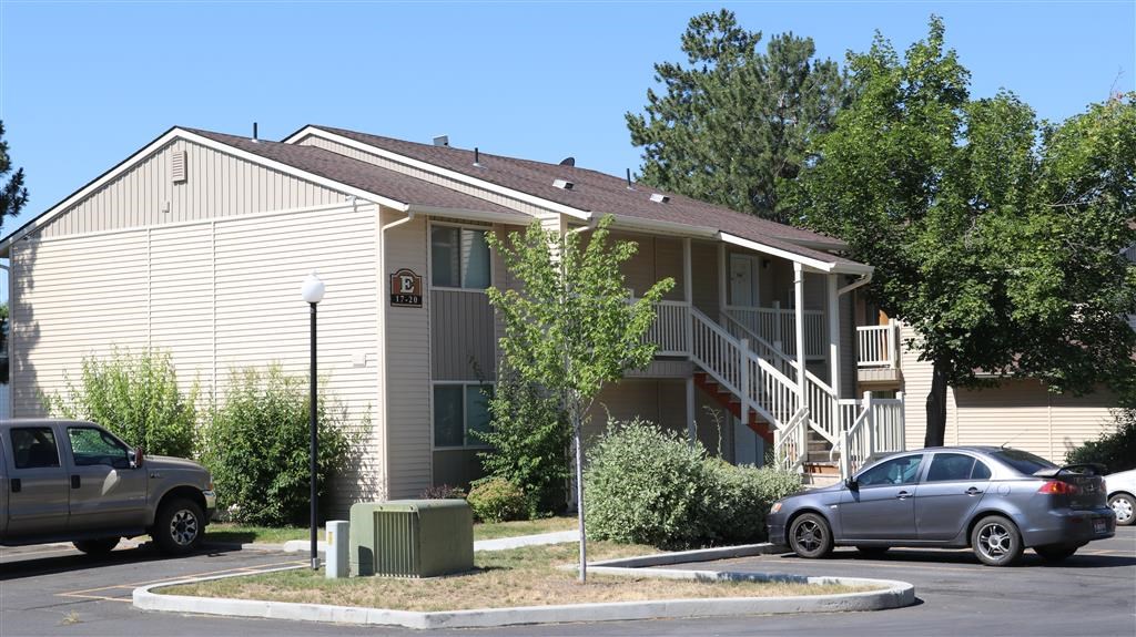 an apartment building with cars parked in a parking lot