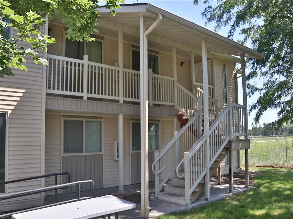 the front of a tan house with a porch and stairs