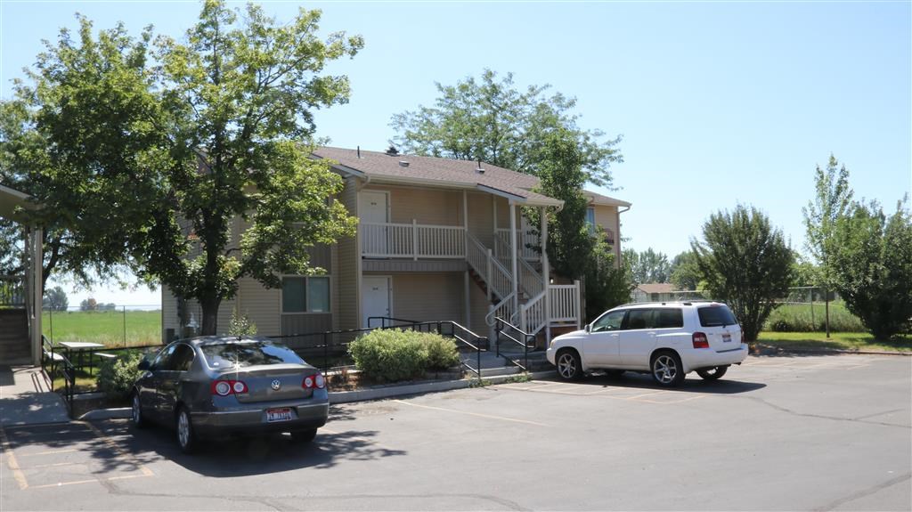 an apartment building with two cars parked in a parking lot