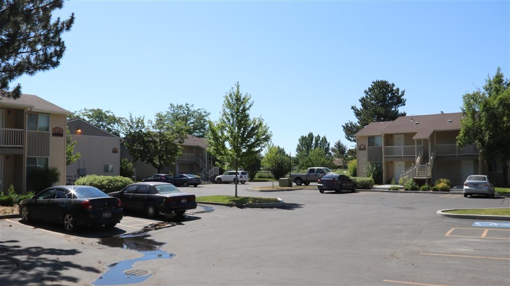 a parking lot with cars in front of apartment buildings
