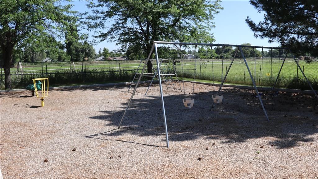 a swing set in a park with a field in the background