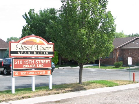a sign in front of a parking lot with a tree