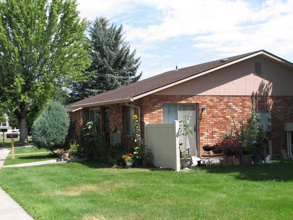 a red brick house with a lawn and trees