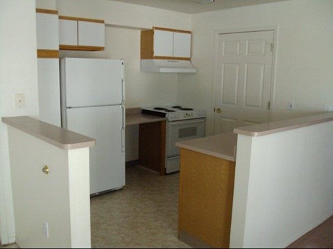 an empty kitchen with a refrigerator and a stove