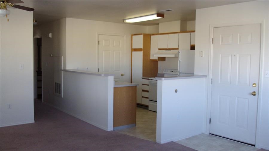 an empty kitchen with white cabinets and an open door