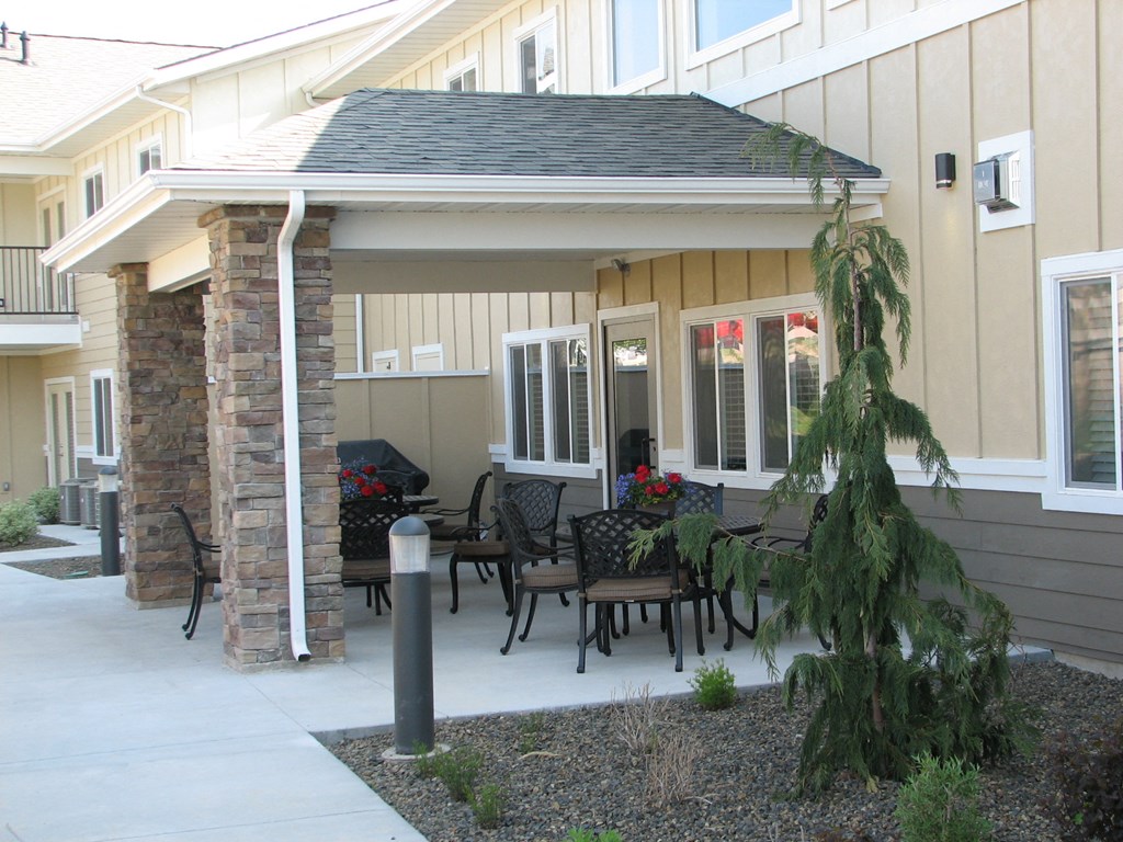 a patio with a table and chairs in front of a house