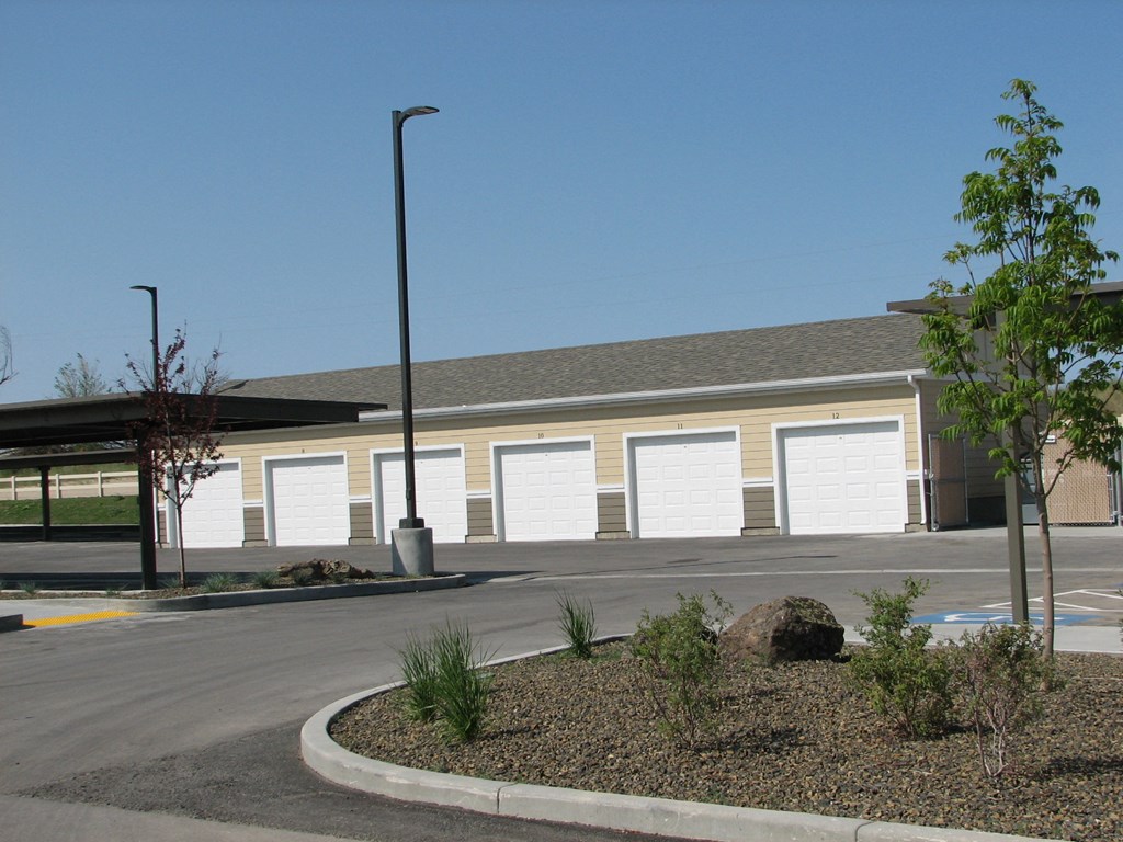 an empty parking lot in front of a building with white garage doors