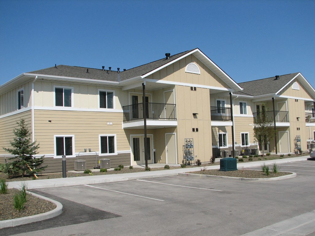 a row of yellow apartment buildings with a parking lot