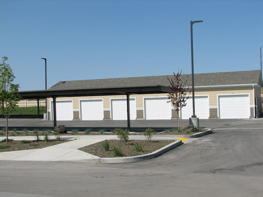 an empty parking lot in front of a building with white garage doors