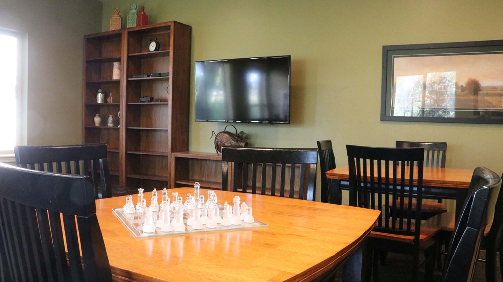 a board game table in a room with chairs and a tv