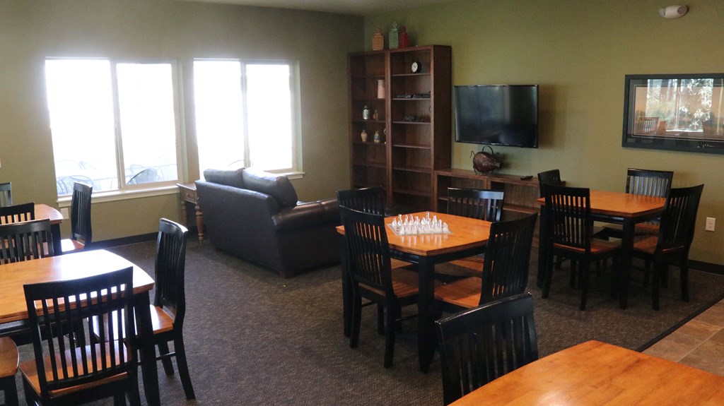 a dining room and living room with tables and chairs and a tv